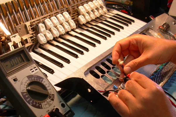 Hands working on accordion electronics beside the keyboard